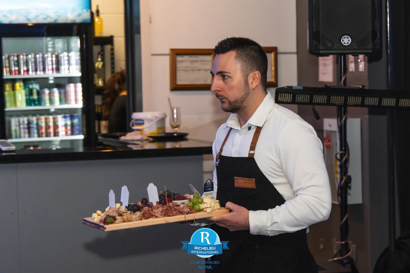 Un serveur transporte fièrement un plateau de charcuteries et de fromages pendant une activité du Club Richelieu d'Alma.
